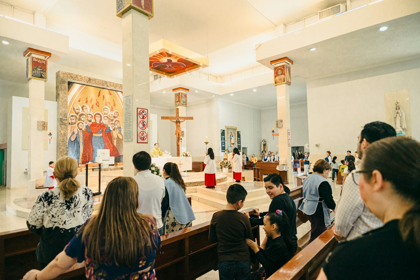 People standing in church pews facing the altar.