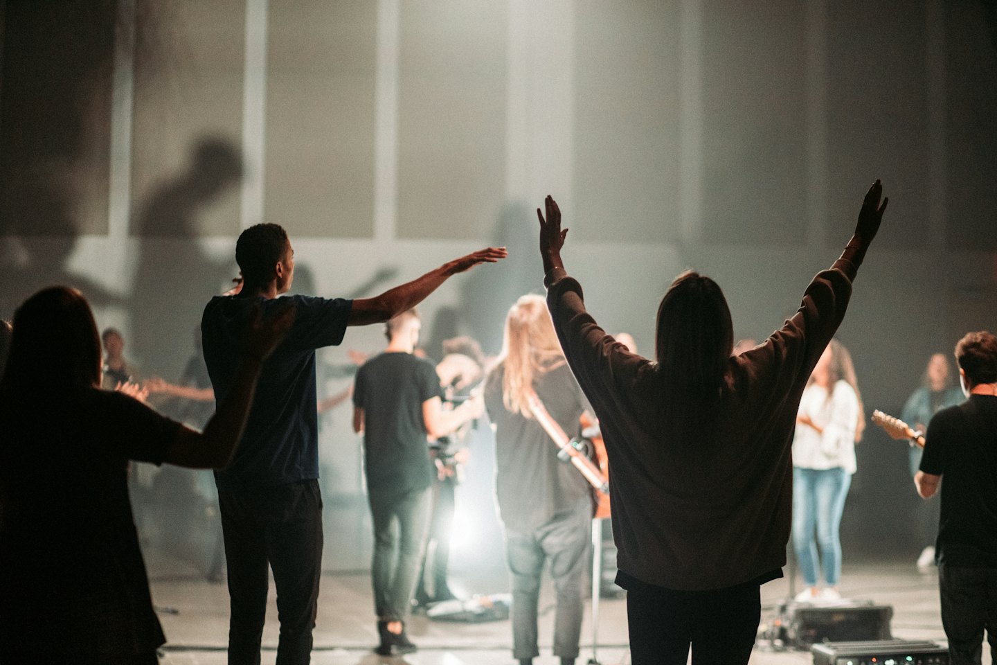 People raising hands in a dimly lit event venue.